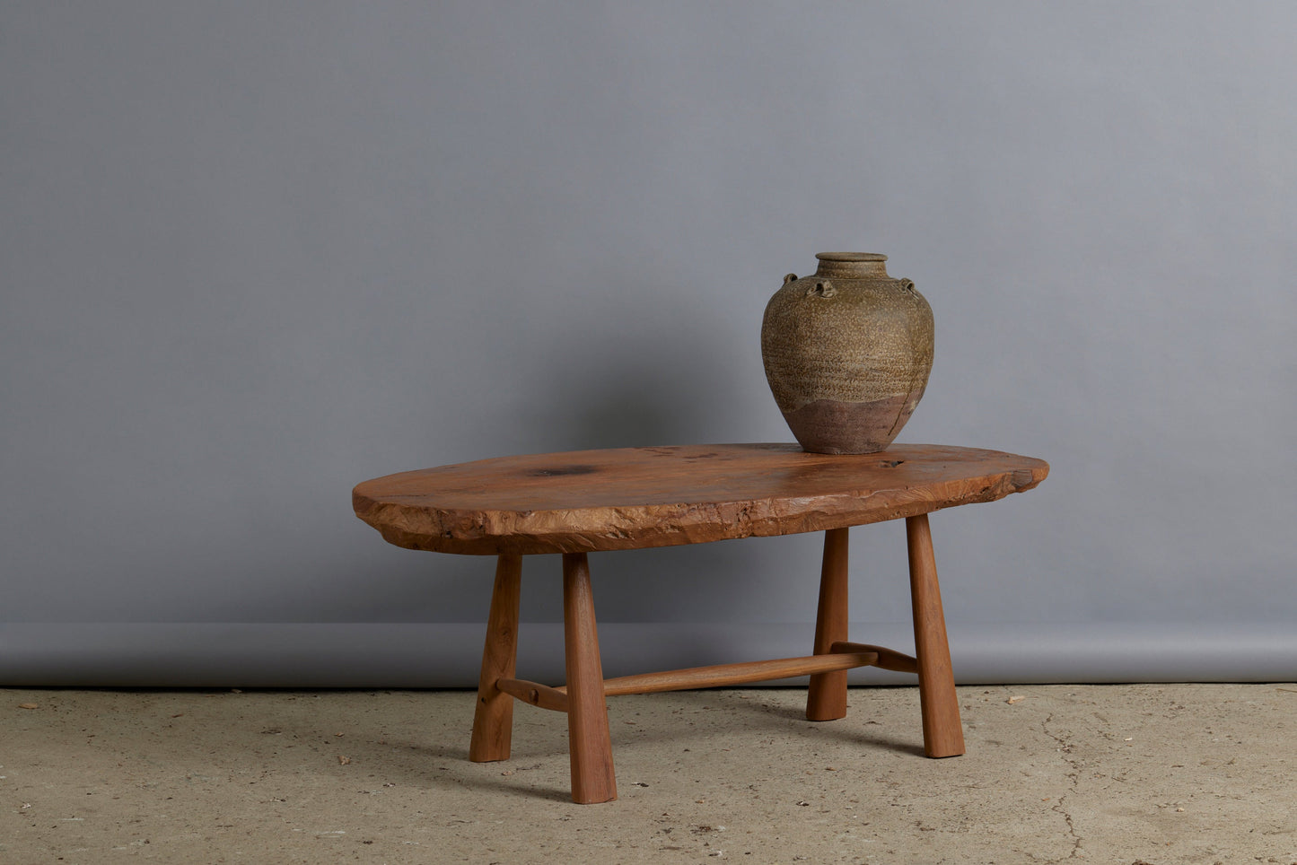 Primitive Oval Top Burled Teak Coffee Table with a Turned Stretcher Base